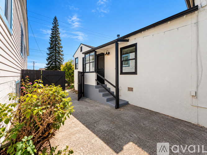 A small white building with a black door and steps leading up to it.