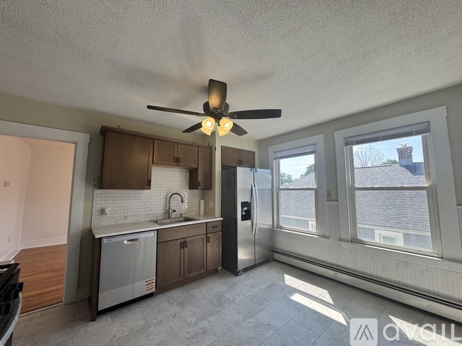 A kitchen with a refrigerator, sink, and cabinets.