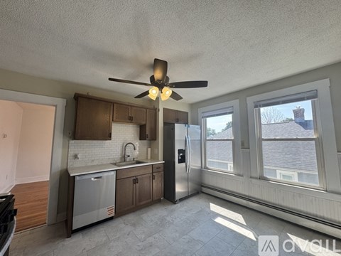 A kitchen with a refrigerator, sink, and cabinets.