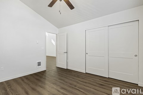 A room with a ceiling fan and three white doors.