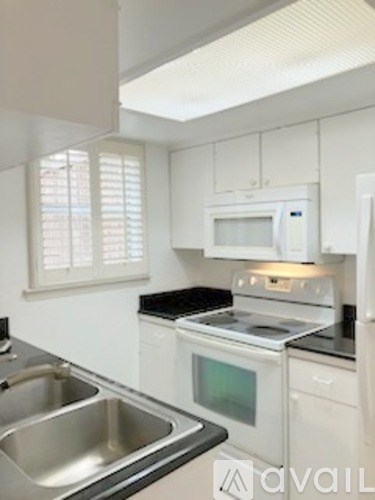 A kitchen with white cabinets and a stove top oven.