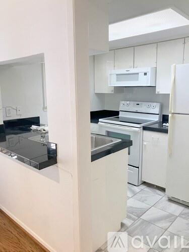 A kitchen with white appliances and black countertops.