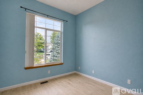 A room with a window and a view of trees and a house.
