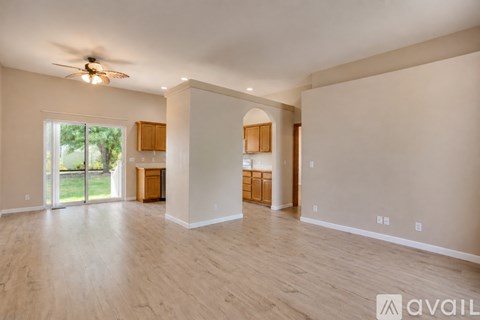 A spacious room with wooden floors and a ceiling fan.