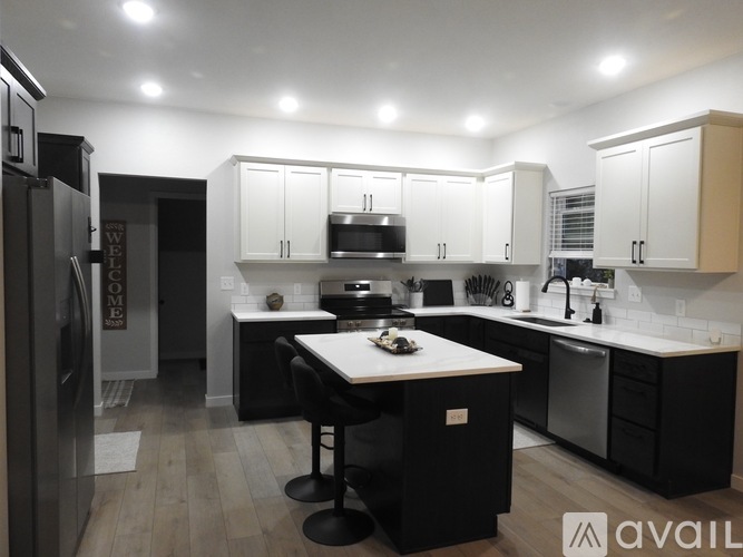 A modern kitchen with white cabinets and black countertops.