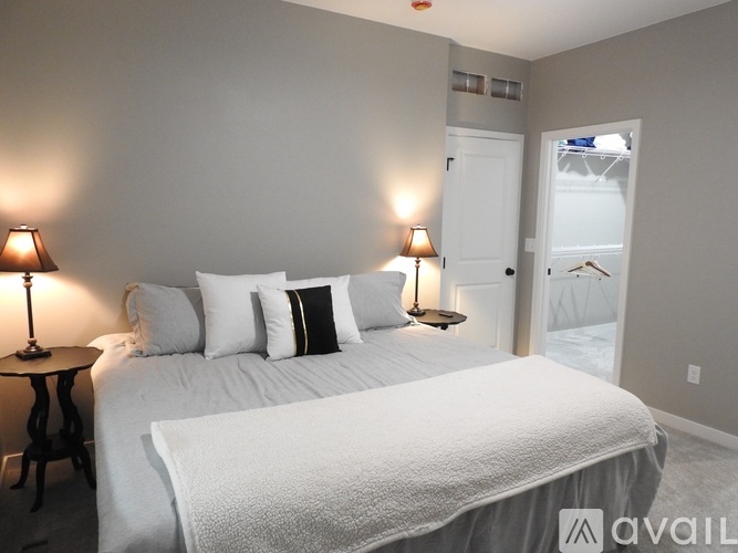 A bedroom with a large bed and two lamps on either side of the bed.