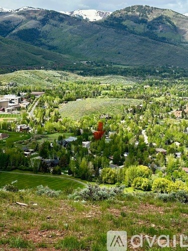 A small town with houses and trees in the foreground and mountains in the background.
