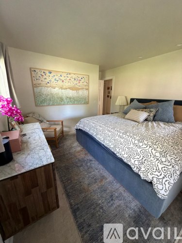 A bedroom with a large bed and a painting on the wall.