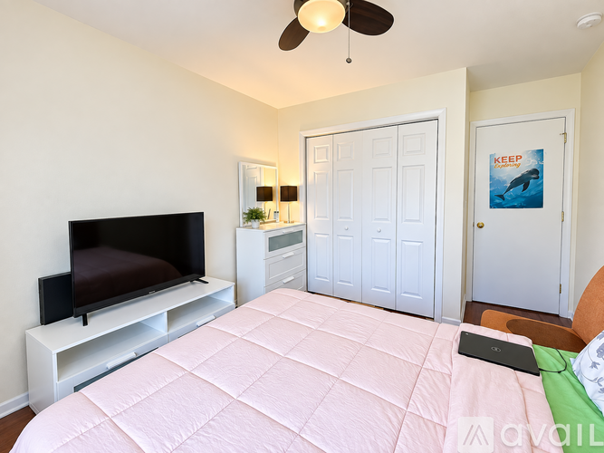 A bedroom with a bed, a television, and a wall-mounted fan.