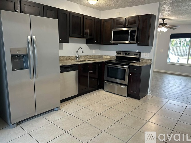 A kitchen with a refrigerator, microwave, oven, and sink.