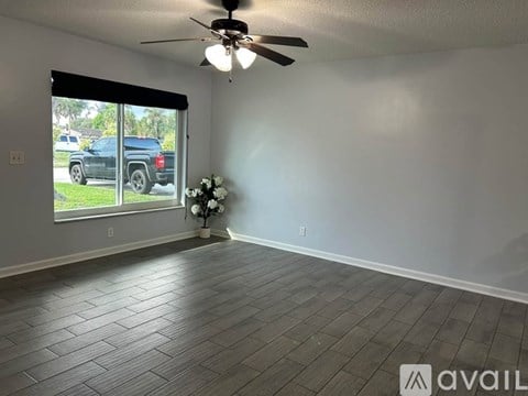 A room with a ceiling fan and a bouquet of flowers on the floor.