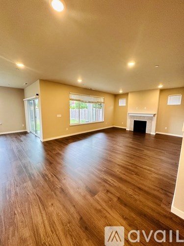 A spacious room with wooden flooring and a fireplace.