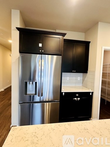 A kitchen with a stainless steel refrigerator and black cabinets.
