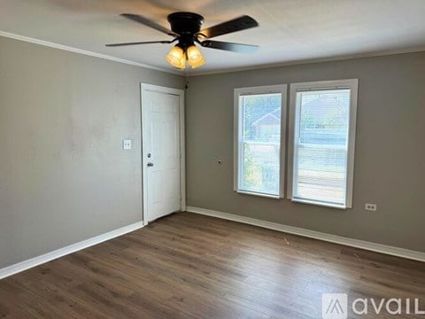 A room with a ceiling fan and a window with blinds.