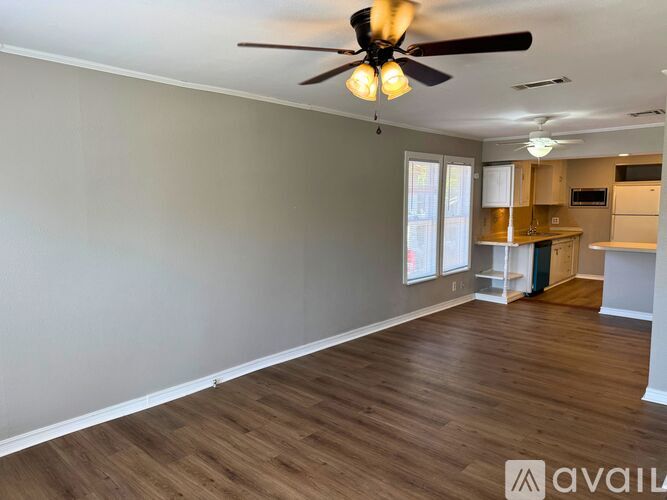 A room with a ceiling fan and wooden flooring.
