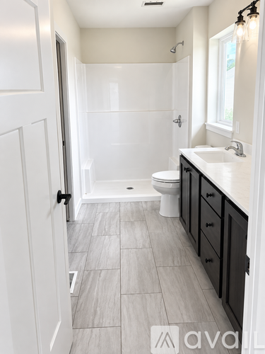 A bathroom with a walk-in shower, toilet, and sink.