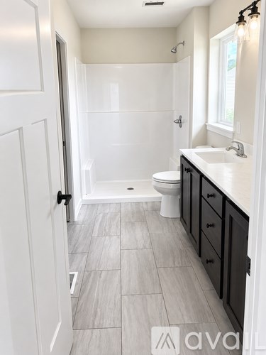 A bathroom with a walk-in shower, toilet, and sink.