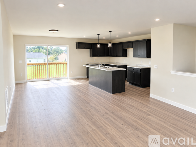 A spacious kitchen with black cabinets and a wooden floor.
