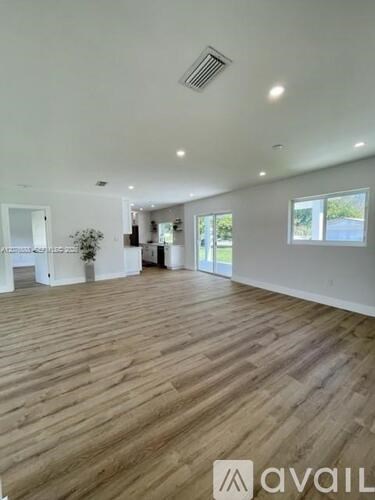 A spacious room with wooden flooring and white walls.