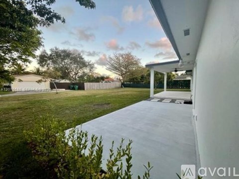 A white building with a patio and a tree in the background.
