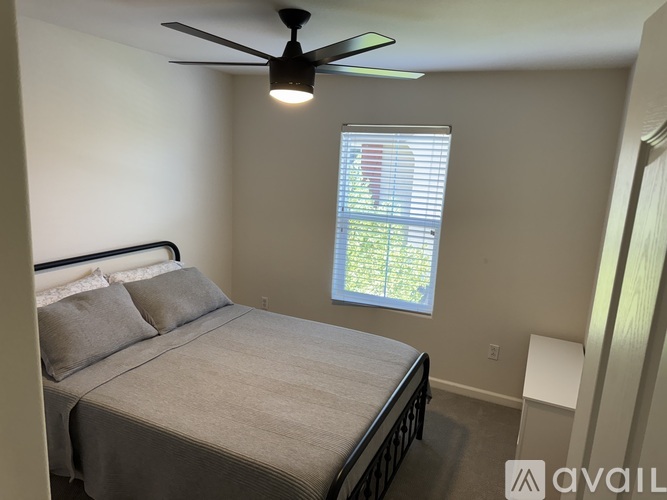 A bedroom with a bed, a ceiling fan, and a window with blinds.