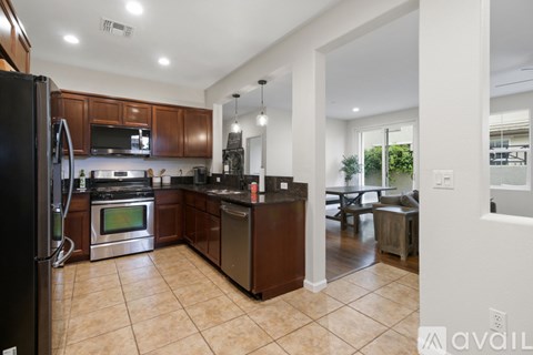 A kitchen with brown cabinets and a black refrigerator.