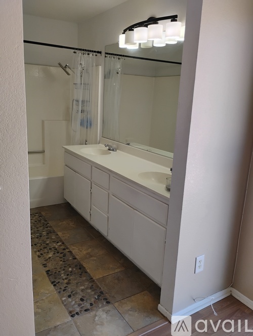 A bathroom with a sink, mirror, and shower.