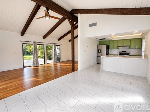 A spacious room with wooden beams and a ceiling fan.