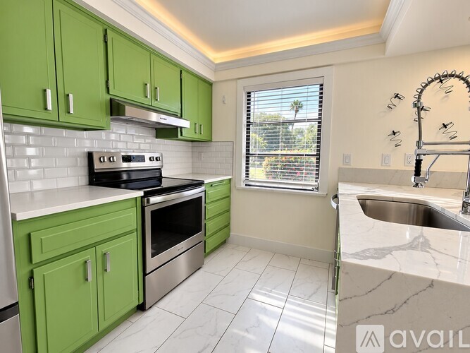 A kitchen with green cabinets and a stainless steel oven.