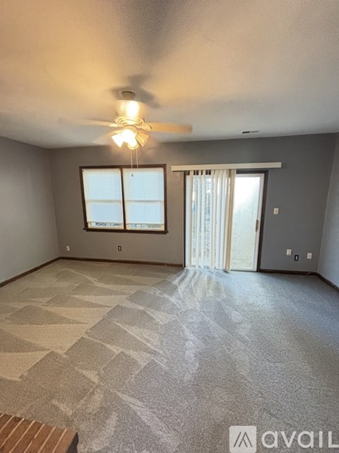 A room with a carpeted floor and a ceiling fan.