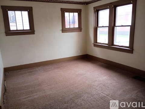 A room with three windows and carpeted floor.