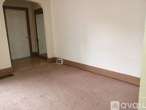 A room with a carpeted floor and a doorway leading to another room.