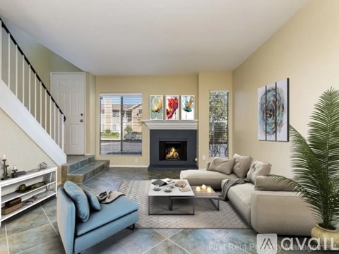 A living room with a fireplace, a couch, a chair, a coffee table, and a potted plant.