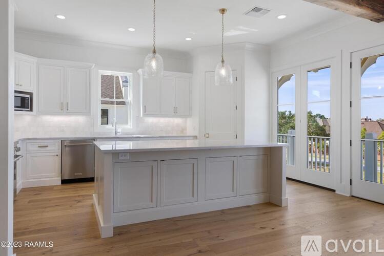 A kitchen with white cabinets and a wooden floor.