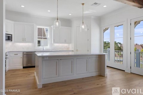 A kitchen with white cabinets and a wooden floor.