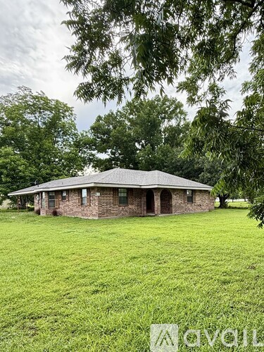 A house with a green lawn and trees in the background.