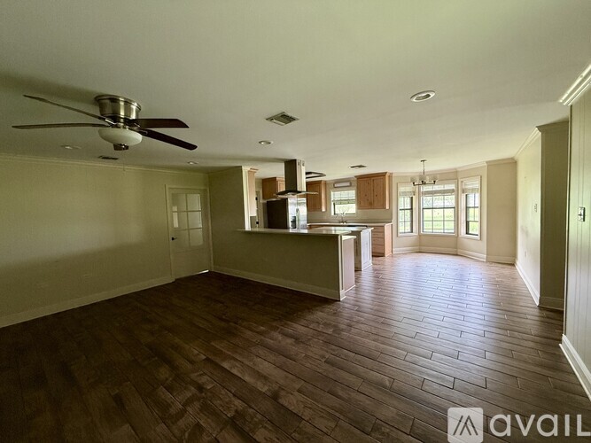 A spacious room with wood flooring and a ceiling fan.