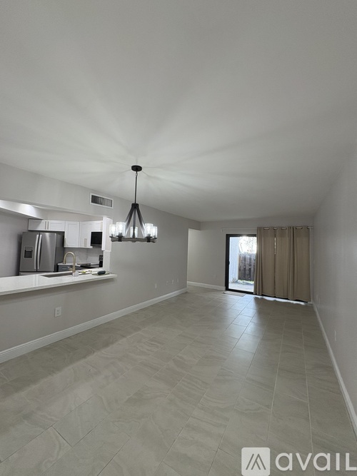 A spacious room with a kitchen area and a dining table.