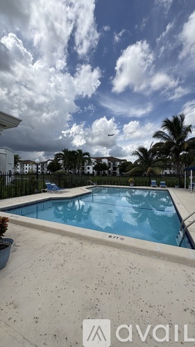 A swimming pool surrounded by a concrete floor and a cloudy sky.