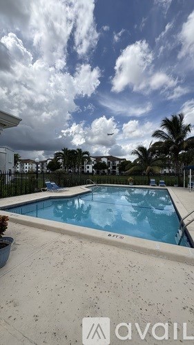 A swimming pool surrounded by a concrete floor and a cloudy sky.