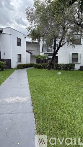 A white building with a tree in front of it.