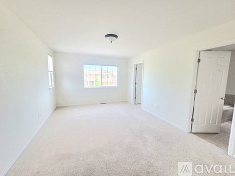 A spacious room with a carpeted floor and a window letting in natural light.