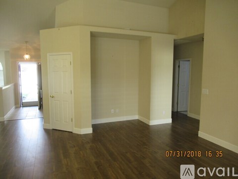 A room with wooden floors and white walls, with a door on the left and another door on the right.