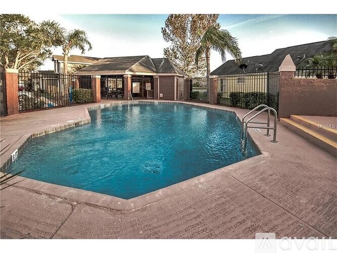 A pool surrounded by a black fence with a house in the background.