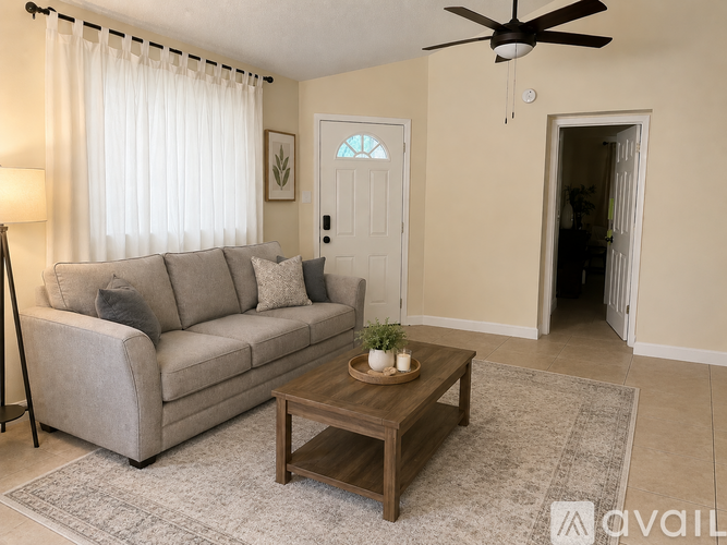 A living room with a grey couch, a wooden coffee table, and a ceiling fan.