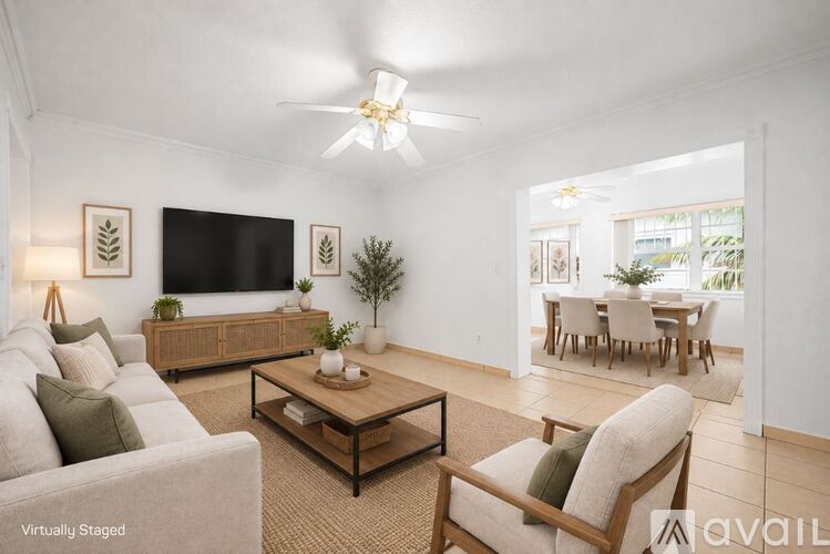 A living room with a white couch, a wooden coffee table, and a flat-screen TV mounted on the wall.