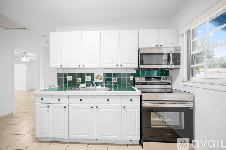 A kitchen with white cabinets and green backsplash.