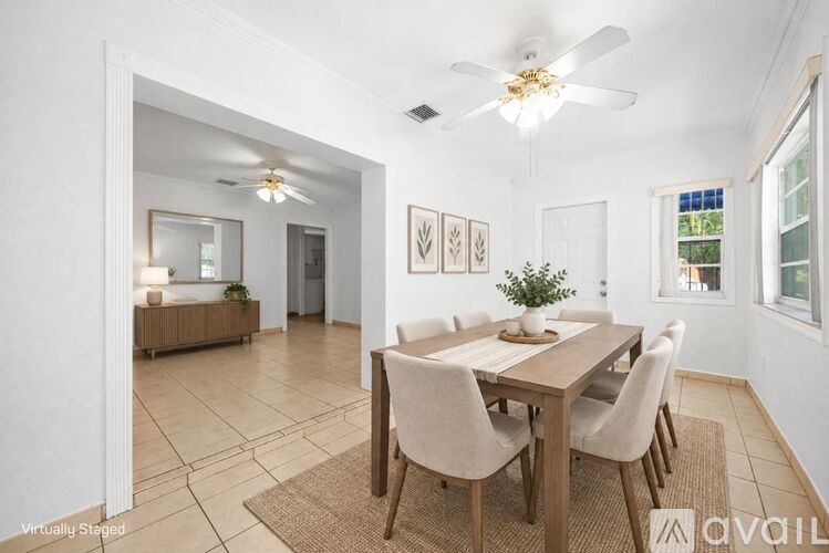 A dining room with a table set for four and a ceiling fan.