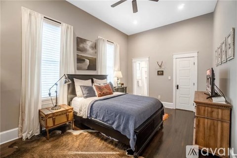 A bedroom with a bed, a nightstand, and a ceiling fan.