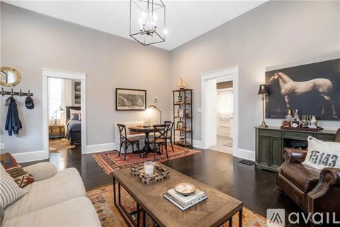 A living room with a white sofa, a wooden coffee table, and a large painting on the wall.